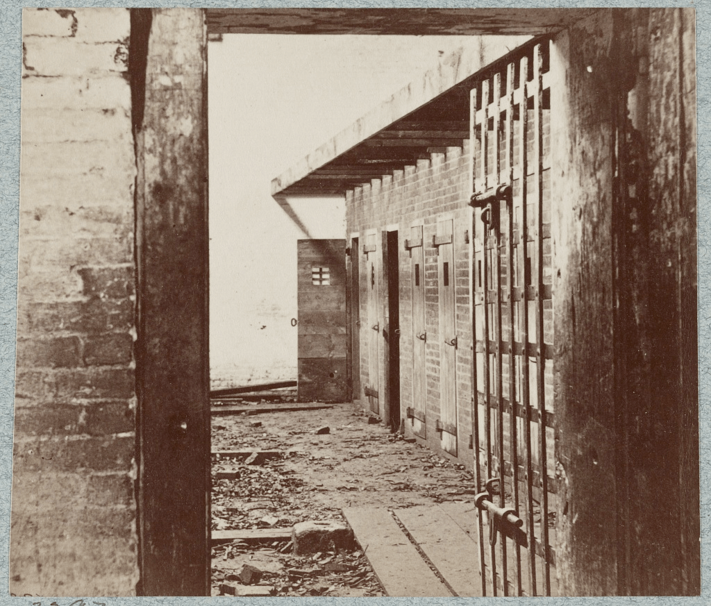 Interior view of a historical slave pen with barred doors and brick walls, showcasing empty cells