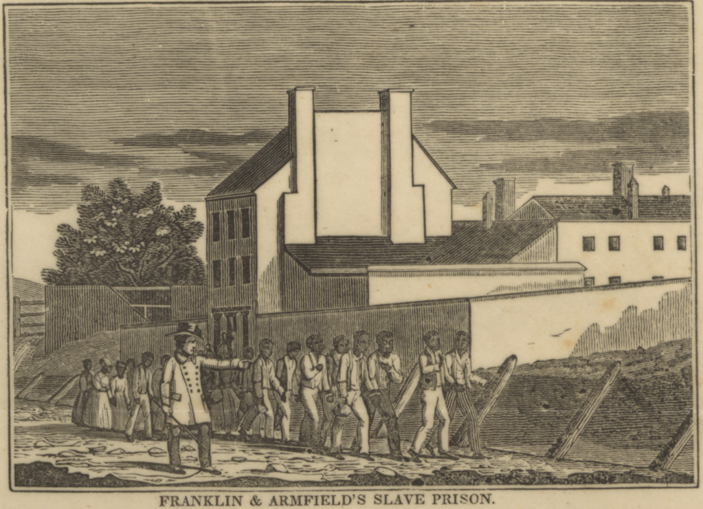 An engraving of Franklin and Armfield's slave prison, featuring enslaved individuals being marched past a large building with multiple stories and a walled enclosure.